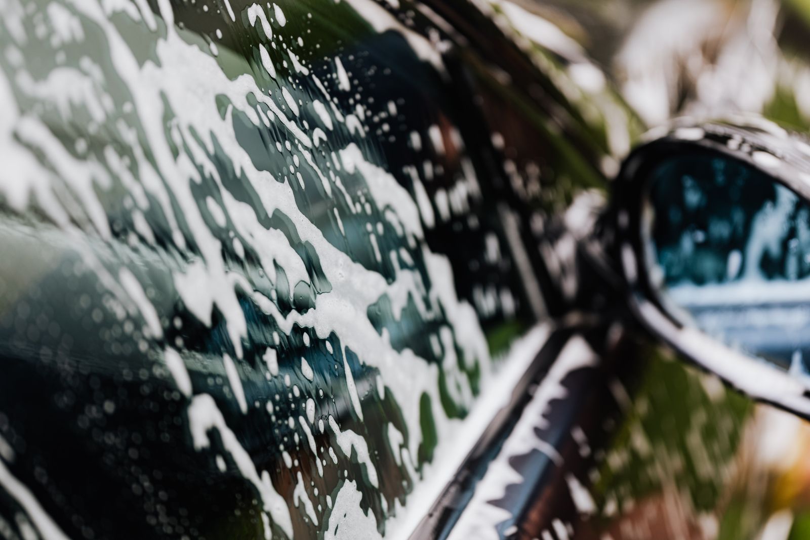 Car covered in soap foam inside a Spectra wash tunnel