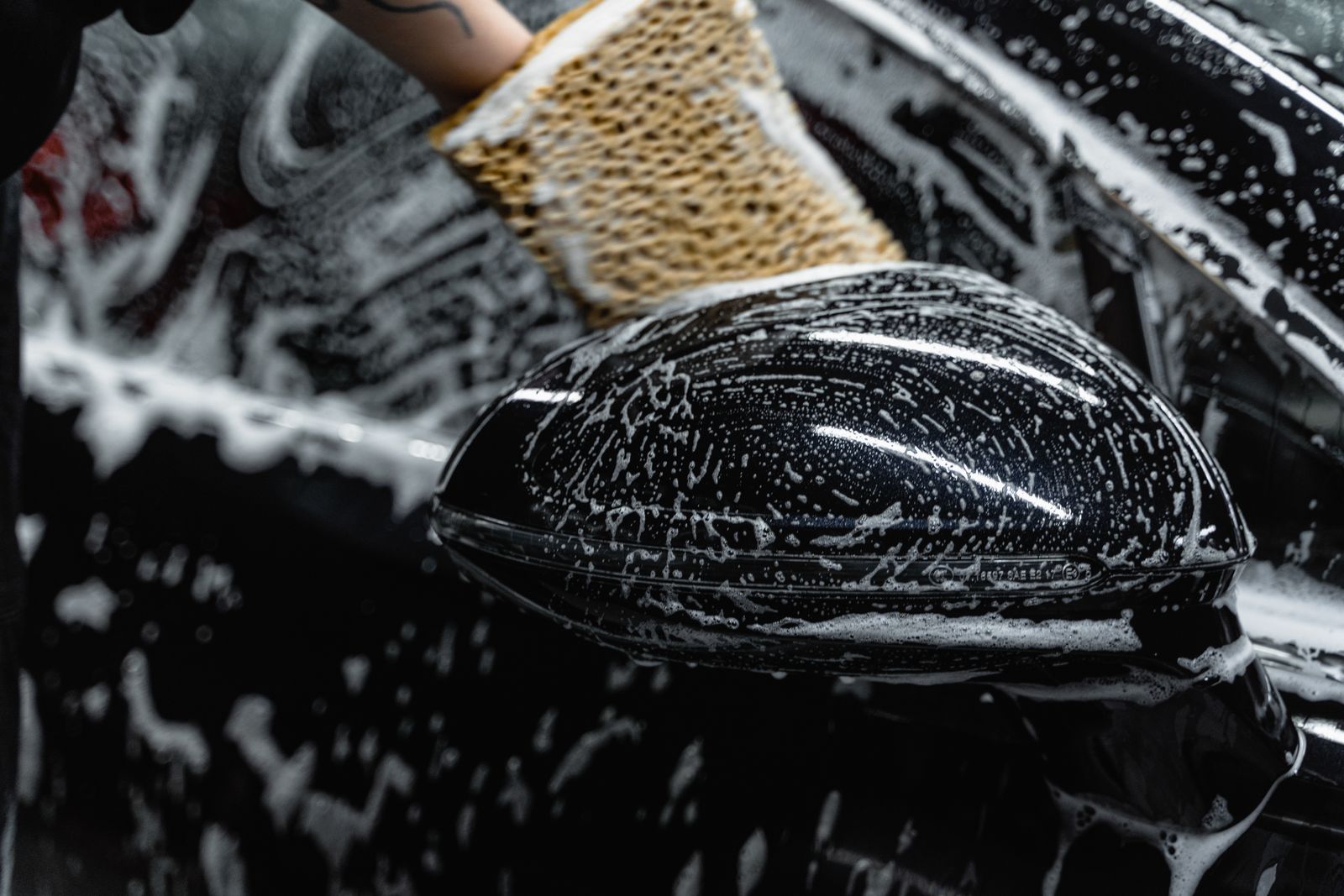 Hand scrubbing a car mirror at a Spectra wash